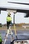 Male Worker Refueling Airplane While Standing On Ladder