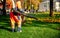 Male worker removes leaf blower leaves lawn of garden Autumn