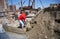 Male worker shoveling sand-cement mix at construction site.