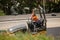 Male worker sitting on a heavy road roller just after fresh bitumen has been layed on a suburban sidestreet