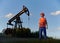 Male worker standing near petroleum pump jack in oil field.