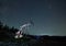 Male worker standing near pump jack under night starry sky.