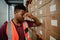 Male worker stressing after being threatened with retrenchment leaning against cardboard packages in warehouse