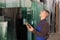 Male worker using control panel and lifting mechanism controls movement of window panes in an industrial workshop