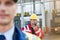 Male worker using walkie-talkie with colleague in foreground at shipyard