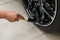 A male worker washes a black car with a special brush for cast wheels and scrubs the surface to shine in a vehicle detailing