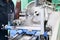 A male worker works on a larger metal iron locksmith lathe, equipment for repairs, metal work in a workshop at a metallurgical