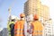 Male workers engineers at construction site real estate in helmets hardhats look at high-rise building skyscraper