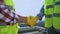 Male workers in safety jackets and gloves shaking hand, partnership agreement