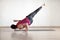 Male yoga practice, advanced level. Caucasian fit man doing side handstand with one leg up in fitness loft studio indoor