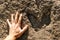 Males hand next to a ancient dinosaur footprint