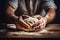 Males hands kneading dough on wooden table. Close up