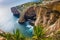 Malta - The famous arch of Blue Grotto cliffs with green leaves