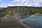 Malta island, near of golden bay, sea coast erosion, grey gravel. Gravel and green bush cliff hills. Blue sea bay