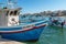 Malta, Marsaxlokk, August 2019. A boat at the pier and a boat with tourists.