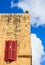 Malta, Mdina. Red window on a yellow sandstone wall in the old medieval city. Blue sky background