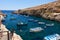 Maltese boats and swimming people in water of Wied Zurrieq Fjord