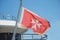 Maltese old flag on pole on ferry`s stern. Ongoing cruise to islands. Blue sky background, close up view