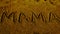 Mama word displayed on sand surface
