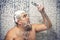 A man of 30-40 years old in a foam stands in the bathroom, looking forward to a shower, water does not pour