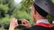 Man in academic dress taking photos of friends on mobile phone, graduation day