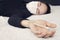 Man with acute male cold measures fever. sick person in wearing a protective medical mask in bed is lying on the bed and holding a