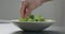 Man add frisee salad leaves into white bowl