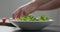 Man add frisee salad leaves into white bowl