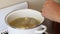The man adds potatoes, carrots and a little salt to the chicken broth. Sorrel soup is boiled in a saucepan. Broth and chicken