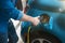 Man adjusting charging cable at electric charging station point standing near blue car