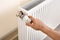 Man adjusting heating radiator indoors