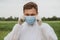 A man adjusts a mask on his face in the outdoors. Quarantine, world pandemic, COVID-19