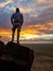 A man admiring a sunrise from a small hill in the suburbs of Xilinhot, Inner Mongolia. The sky is painted in orange, red