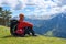 Man adventurer sits on the alpine meadow among the wildflowers