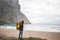 Man adventurer walking by the sea beach among cloudy mountains