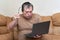 A man at the age of sitting on Devani looks through the news on a laptop.