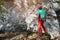 A man aged climber stands in front of a training rock in the forest. Climbing training