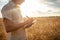 man agronomist in a wheat field. Ripe barley, sunset. The employee calculates losses and profits, evaluates the yield