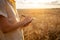 man agronomist in a wheat field. Ripe barley, sunset. The employee calculates losses and profits, evaluates the yield