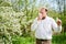 Man allergic using medical nasal drops, suffering from seasonal allergy at spring in blossom garden