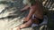 Man alone on the beach drawing on the sand. Getting mad from idleness.