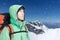 Man alpinist looks up against a winter mountain landscape.