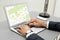 Man analyzing cadastral map on laptop at table, closeup