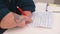A man with anatomical processes on his hands writes a pen with text on paper.
