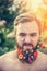 A man with an angry face with a beard with flowers his beard On natural background