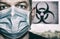 Man with an anxious look in a surgical mask in the background `biohazard sign`