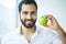 Man With Apple. Beautiful male With White Smile, Healthy Teeth.