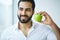 Man With Apple. Beautiful male With White Smile, Healthy Teeth.