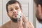 Man is applying shaving foam to his face preparing to shave