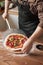 A man in an apron puts a ready-made pizza on a wooden table